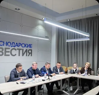 Конференц-зал: участники совещания за столом под вывеской «Краснодарские известия»